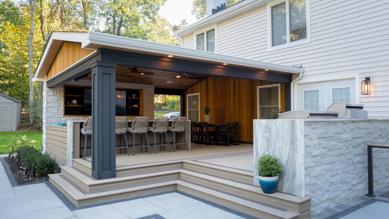 Custom outdoor deck with kitchen, bar seating, and multiple zones for entertaining